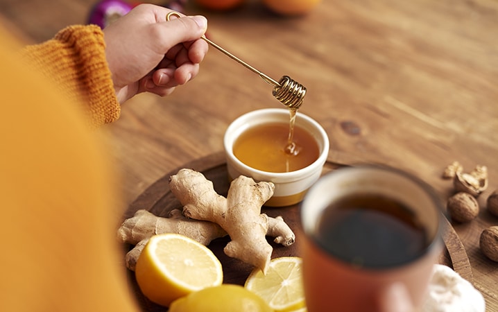 Warming tea with honey, lemon and ginger Honey, Ginger, Sliced Lemon and Tea In a Wooden Tray
